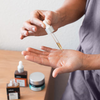 Woman dropping broad spectrum CBD oil into palm with dropper