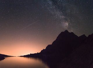 Starry new moon sky at sunrise, with lake and mountain