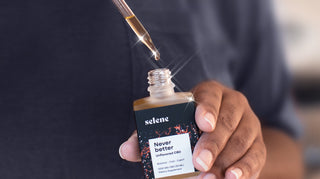 Woman holding broad-spectrum CBD tincture, oil dripping from dropper