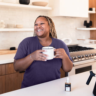 Woman smiling, holding CBD tea: sustainable, organic CBD tincture made for and by women