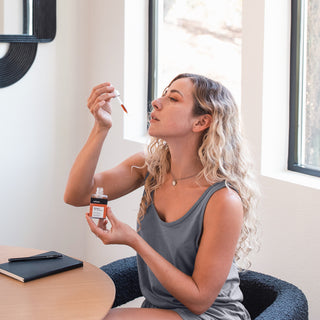 Woman taking CBD and adaptogen tincture, holding dropper to her mouth